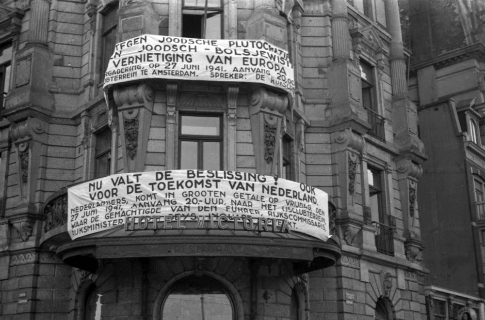 Nationaal-socialistisch spandoek aan het Victoriahotel op het Damrak.